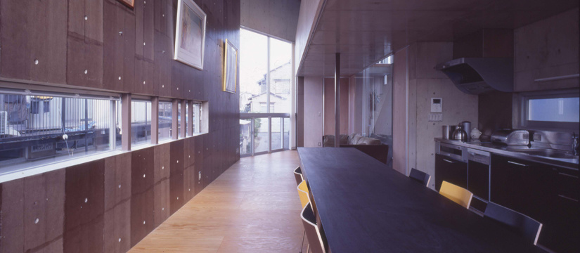 絵画のかかるコンクリート壁と吹抜のあるリビングルーム